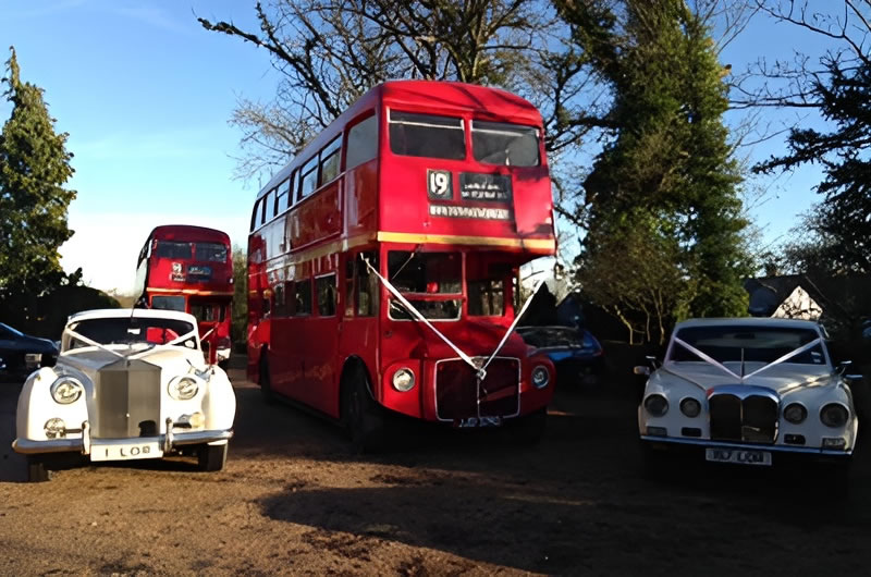 Routemaster wedding bus with ribbons beside two classic wedding cars